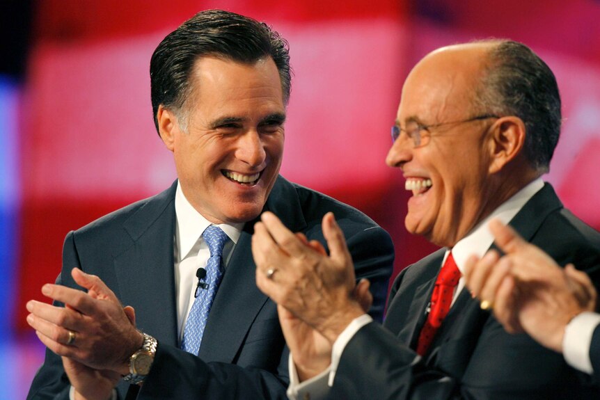 Rudy Giuliani laughing with Mitt Romney on a stage