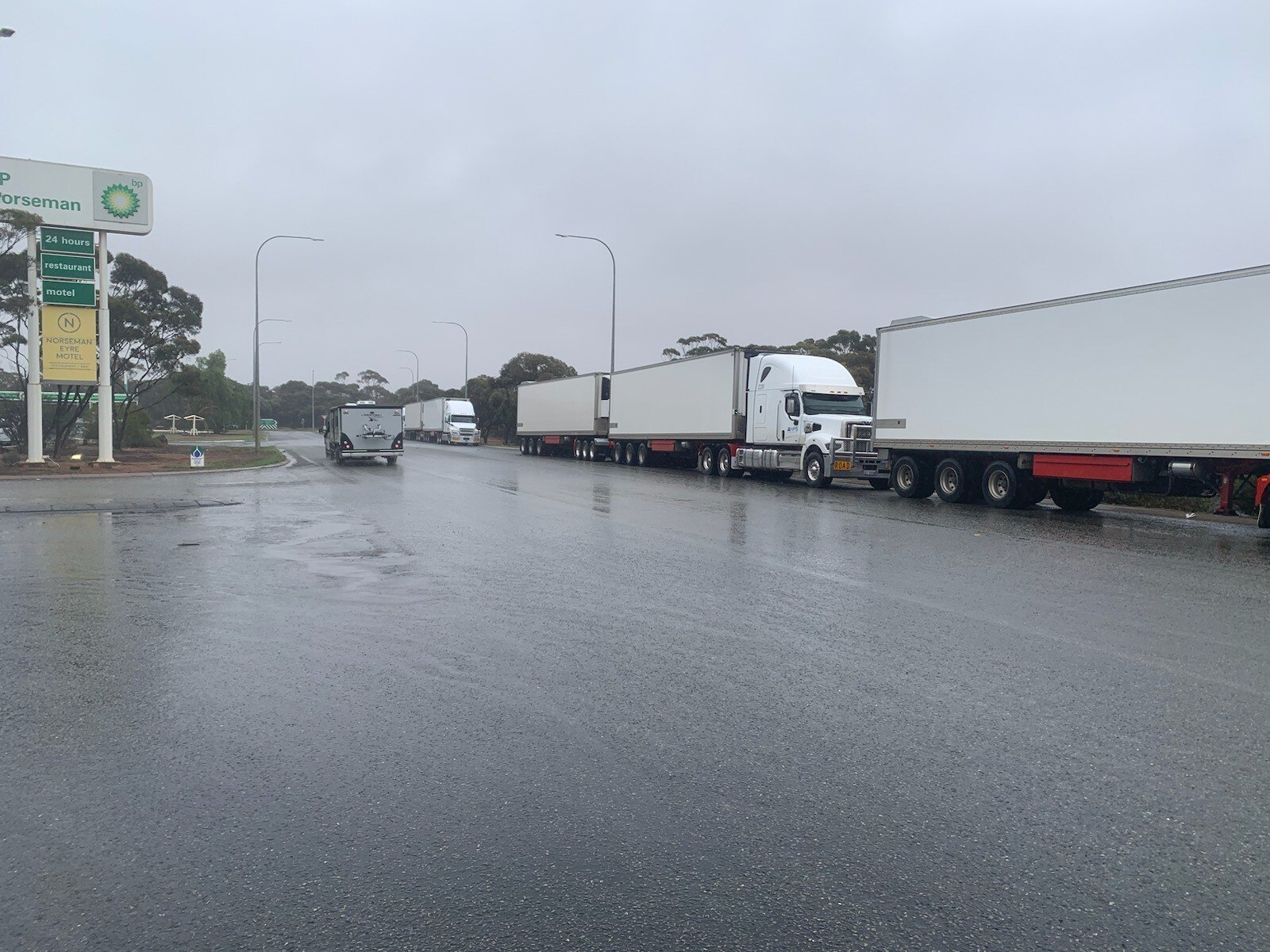 Road trains parked up on a wet road waiting for it to reopen after flooding.  