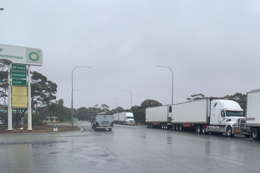 Road trains parked up on a wet road waiting for it to reopen after flooding.  
