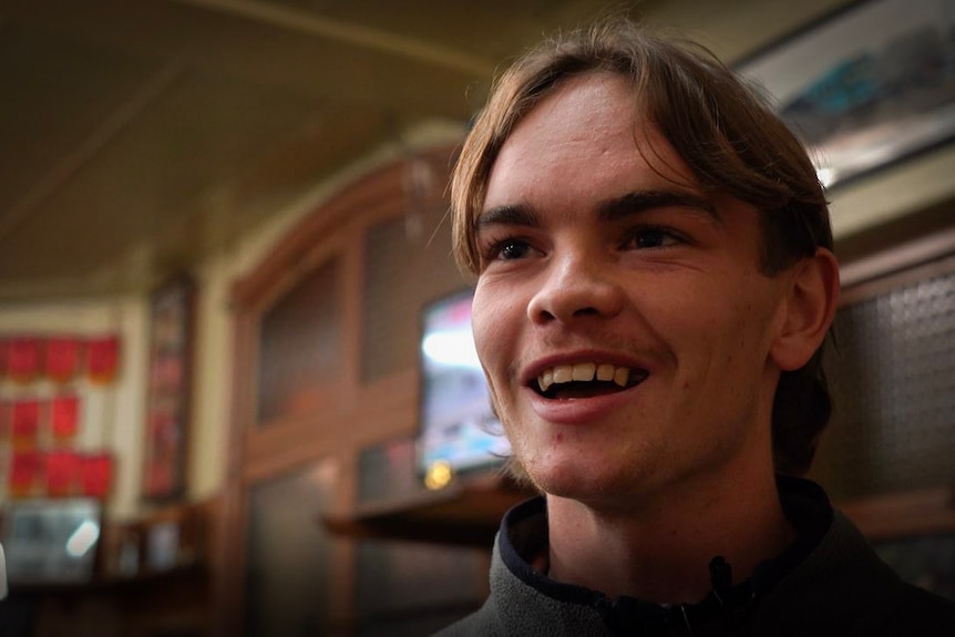 A smiling young man inside a pub.
