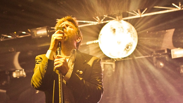 Image of singer James Murphy on stage, with disco ball behind him