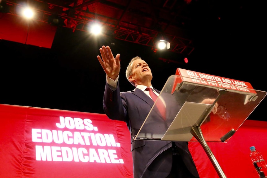 Bill Shorten gestures with his hand as he speaks at a podium.