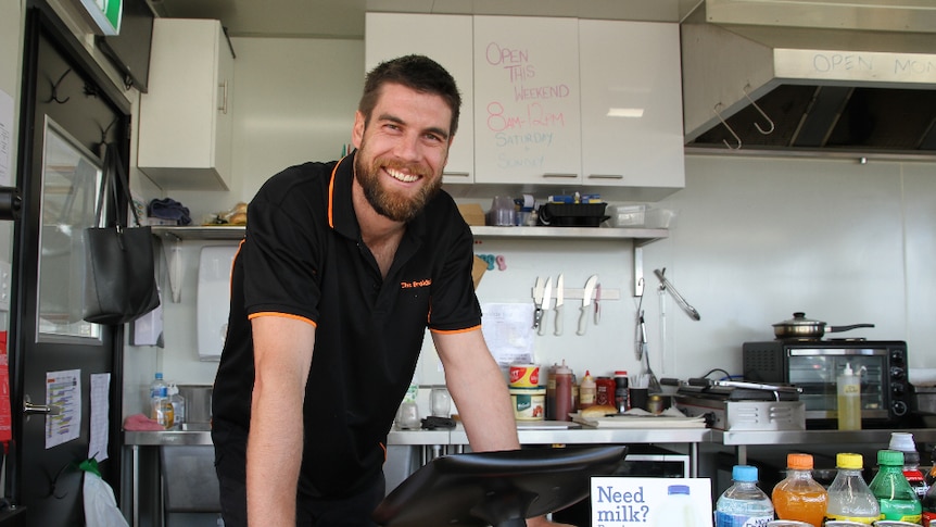 Owner of The Brekkie Box Dylan Connell standing behind the counter looking at the camera.