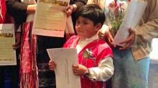 A young boy holds is certificate of citizenship at a ceremony in Hobart.
