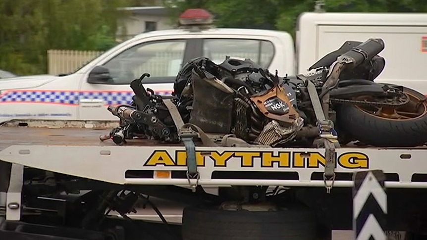 A mangled motorcycle on the back of a flat bed tow truck