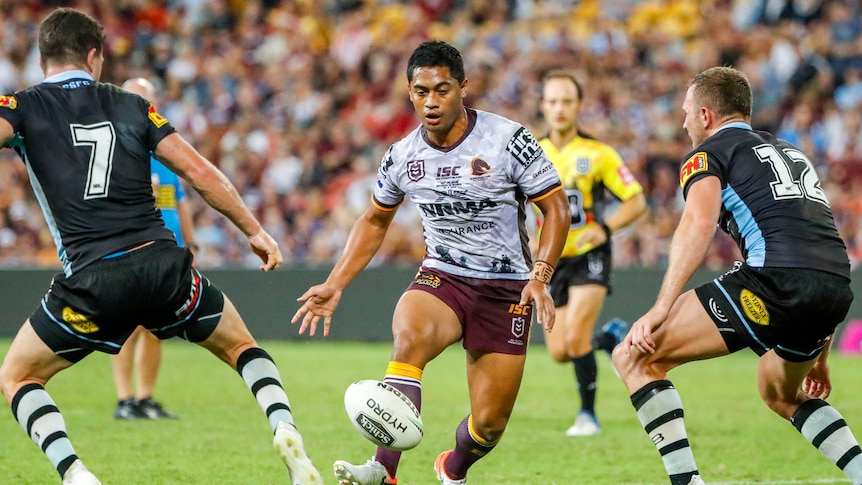 Anthony Milford performs a grubber kick between two Cronulla defenders.