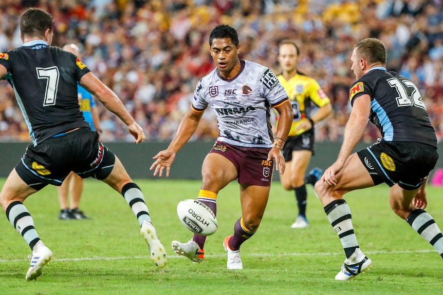 Anthony Milford performs a grubber kick between two Cronulla defenders.