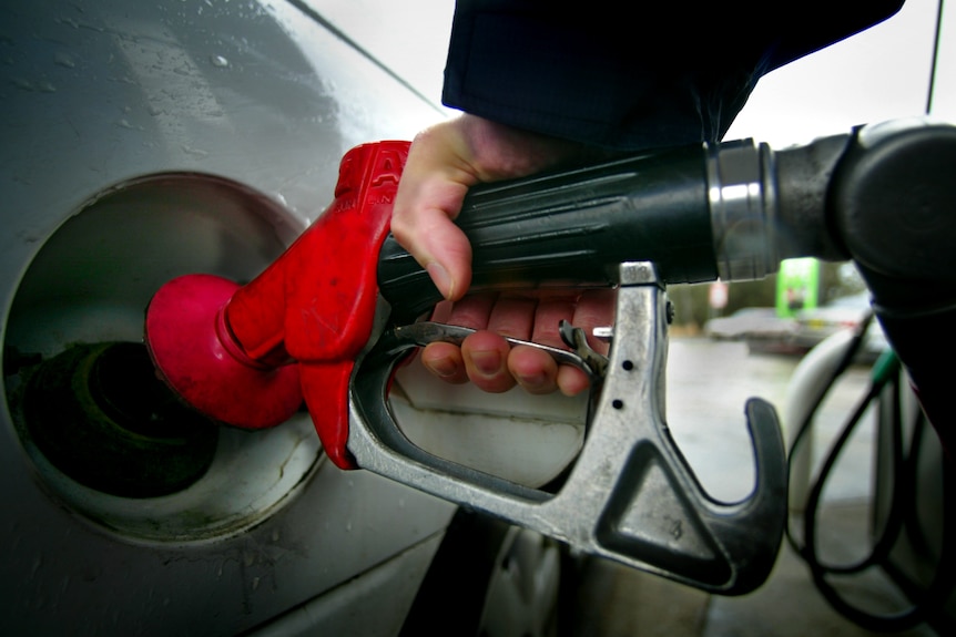 Una mano sostiene al Bowser bombeando gasolina a un auto