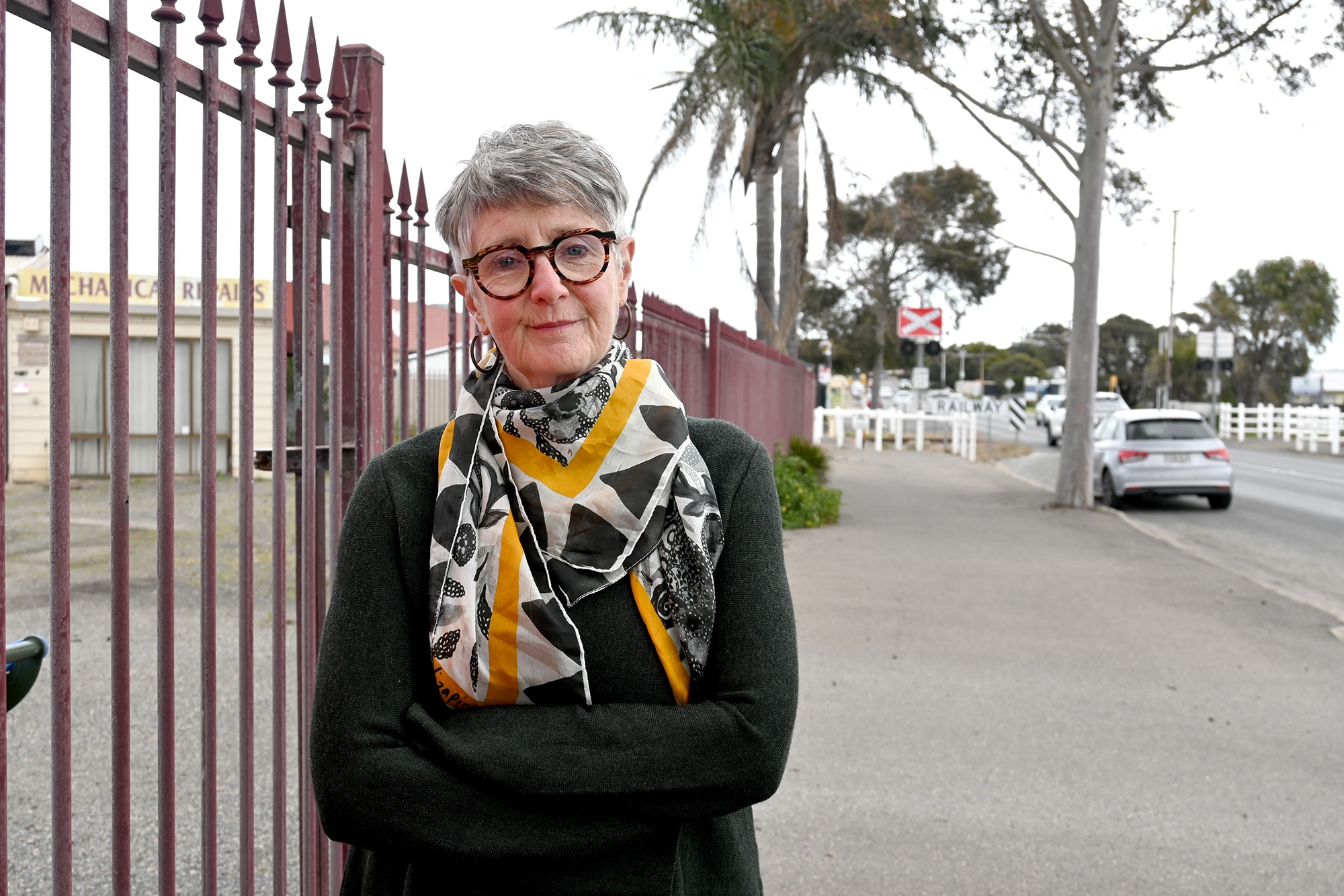 Woman with crossed arms next to a fence
