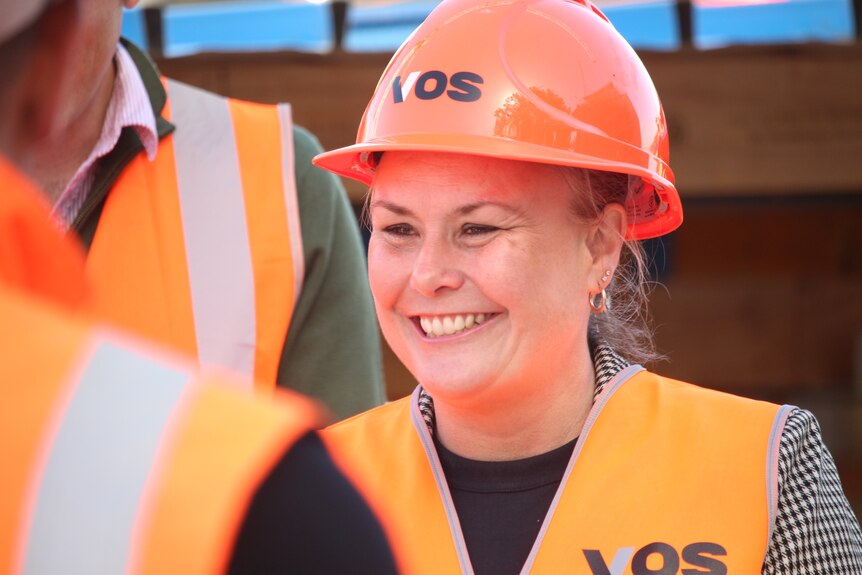Anita Dow smiling and wearing a high-vis orange vest and hard hat.