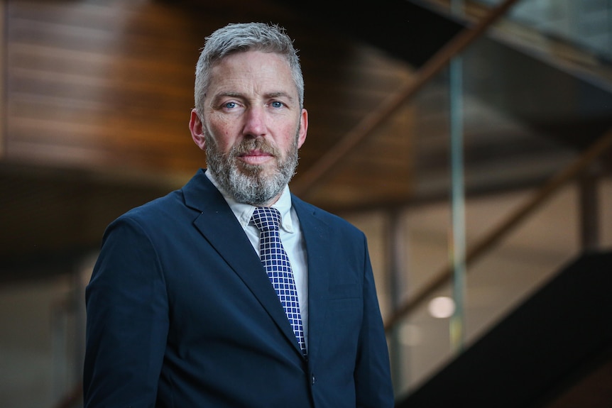 A man in a suit looks at the camera 