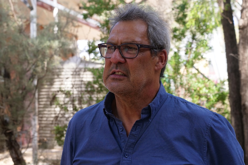 A man wearing glasses and a navy shirt.