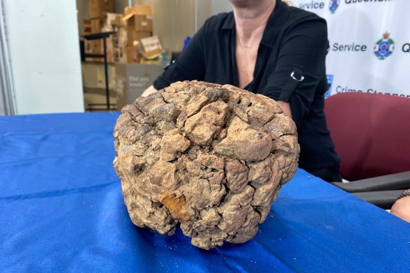 A soccer-ball sized meteorite sits on a table with a blue cloth