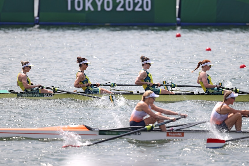 Four women in a boat on the water next to another boat