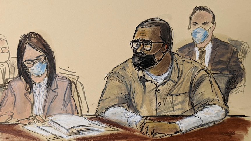 A courtroom sketch of a female attorney wearing a face mask sitting next to R Kelly in prison clothes and a face mask