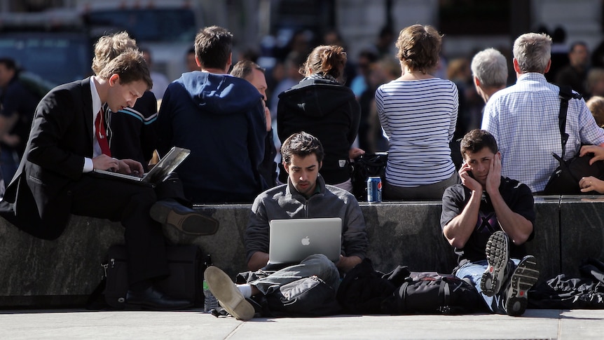 People work on laptops outside.