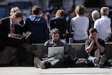 People work on laptops outside.