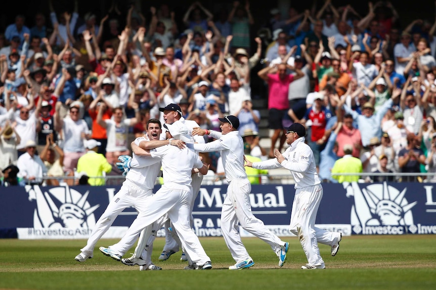 Cricketers crowd around joyously after winning an Ashes Test as the crowd in the background roars.