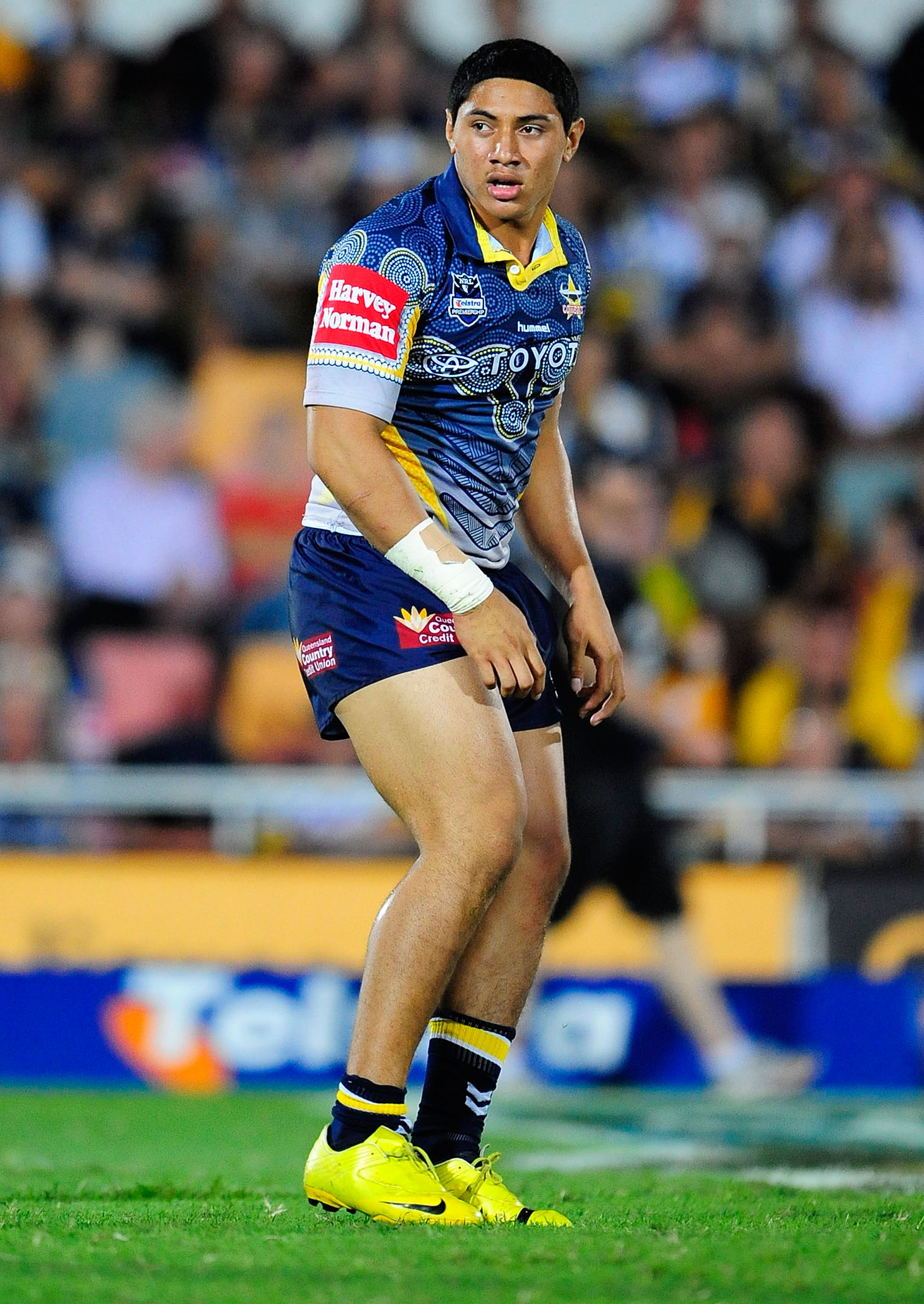 Jason Taumalolo looks on during his NRL debut. Background blurred, crowds can be seen. 