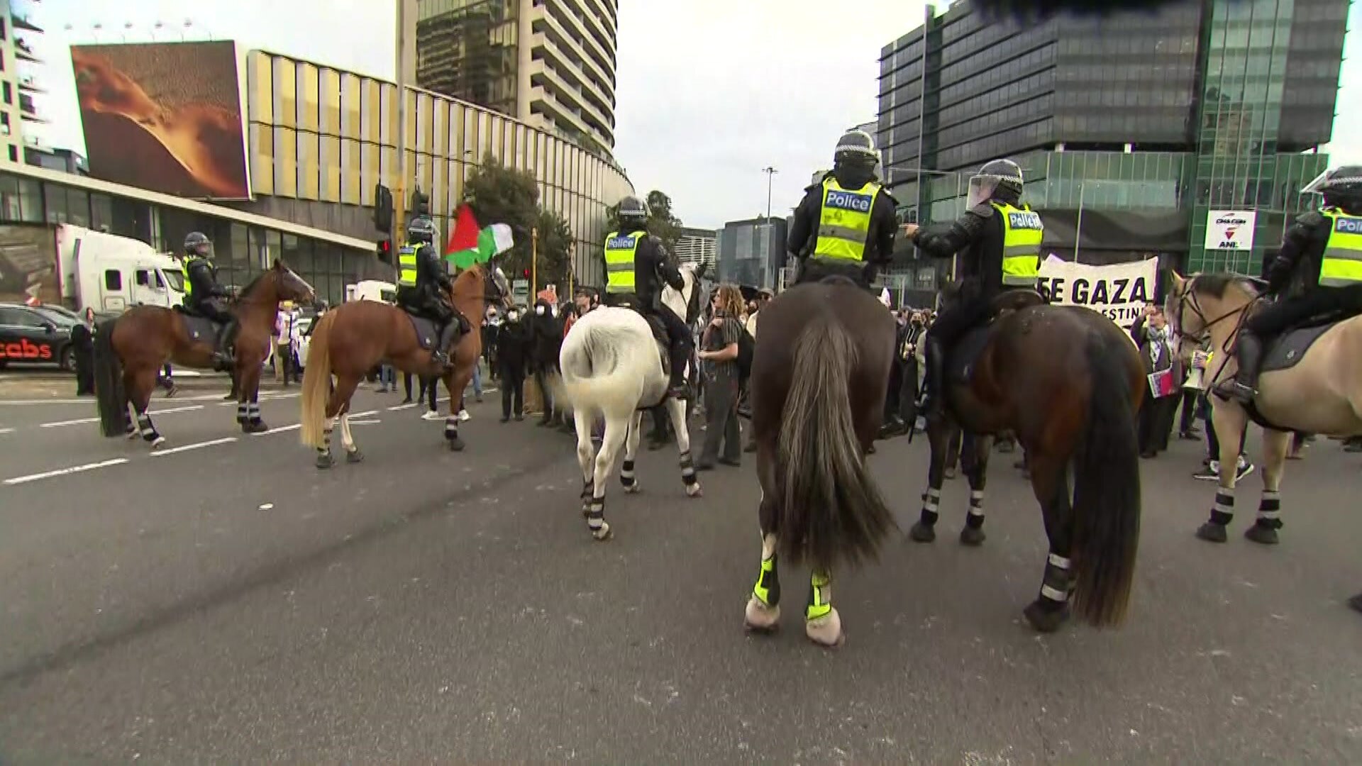 骑马警察站在街上抗议者身后。