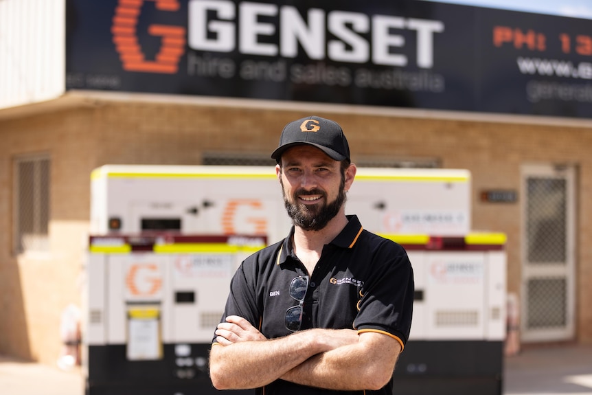A man standing in front of diesel generators at a hire company. 