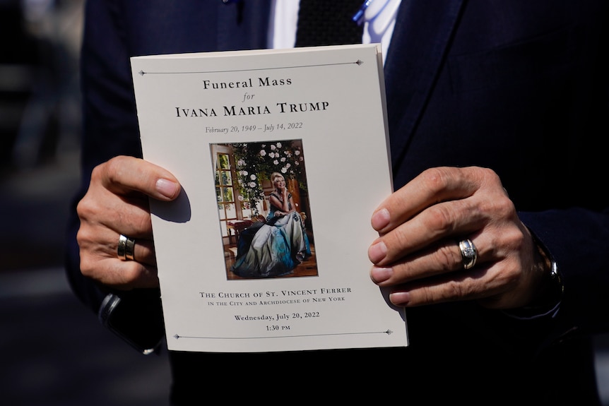 A man holds a program from Ivana Trump's funeral Mass.