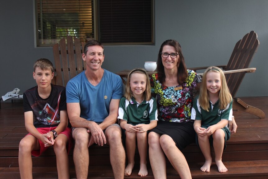 Trevor and Becky Crawford with their two daughters and son sitting outside their family home in Sawtell.