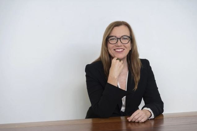 A woman wearing glasses and smiling.