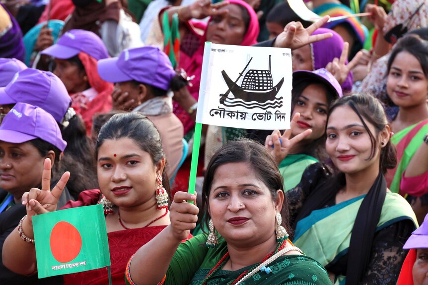 Close up of two female supporters of the ruling Awami League party waving flags.