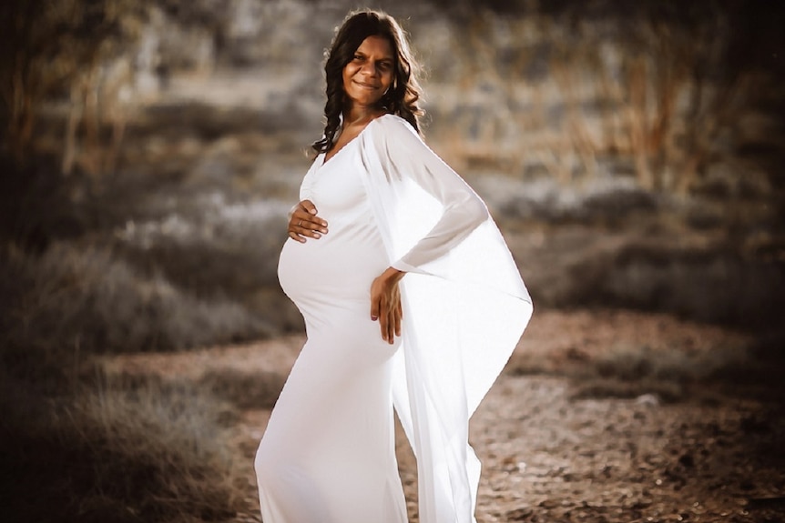 Pregnant Indigenous woman poses for a maternity photoshoot in a white dress