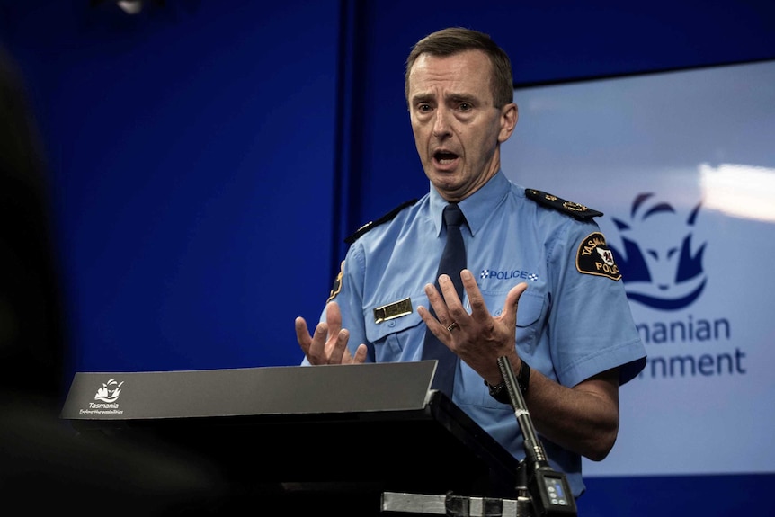 Tasmania Police Commissioner Darren Hine gestures at a lectern.