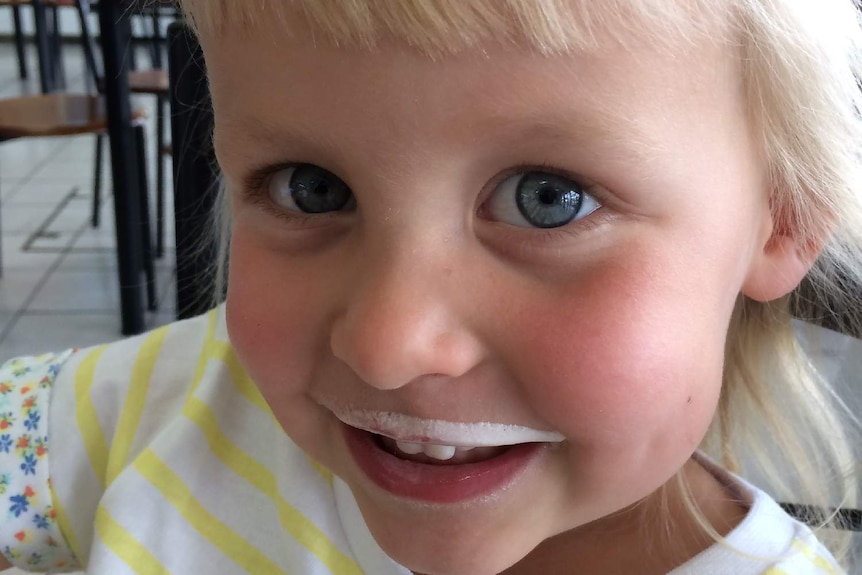 Monique Squires smiles at the camera with a milk moustache.