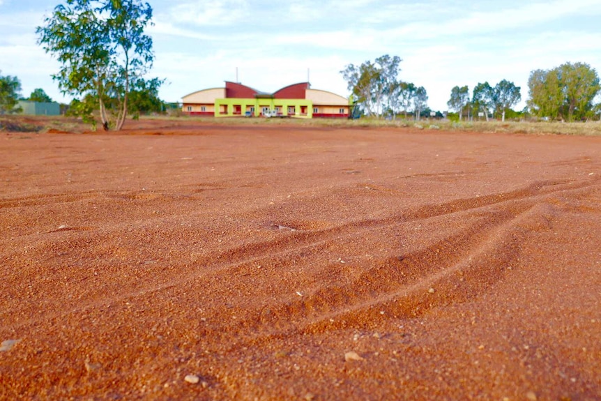 A red sandy area with a building in the background.