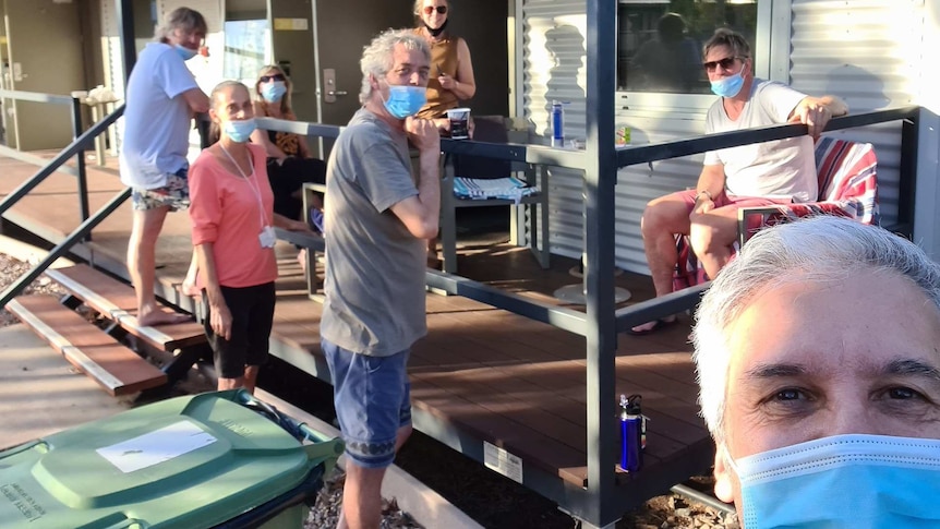 David Desira takes a selfie with six other people in quarantine in the background on a balcony.