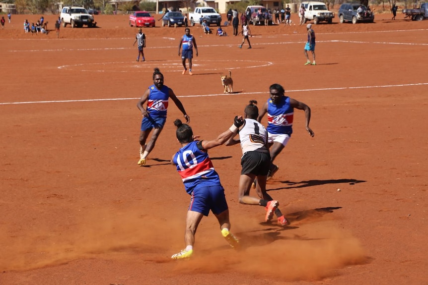 The Mimili Blues players on a red dirt oval.