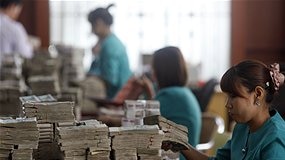 Burmese bank worker counts money.