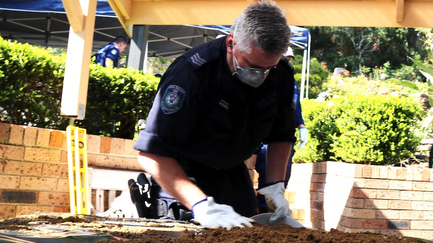 A police officer searching through dirt on a table