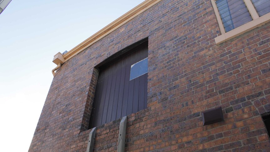 A large door high up in a brick wall.