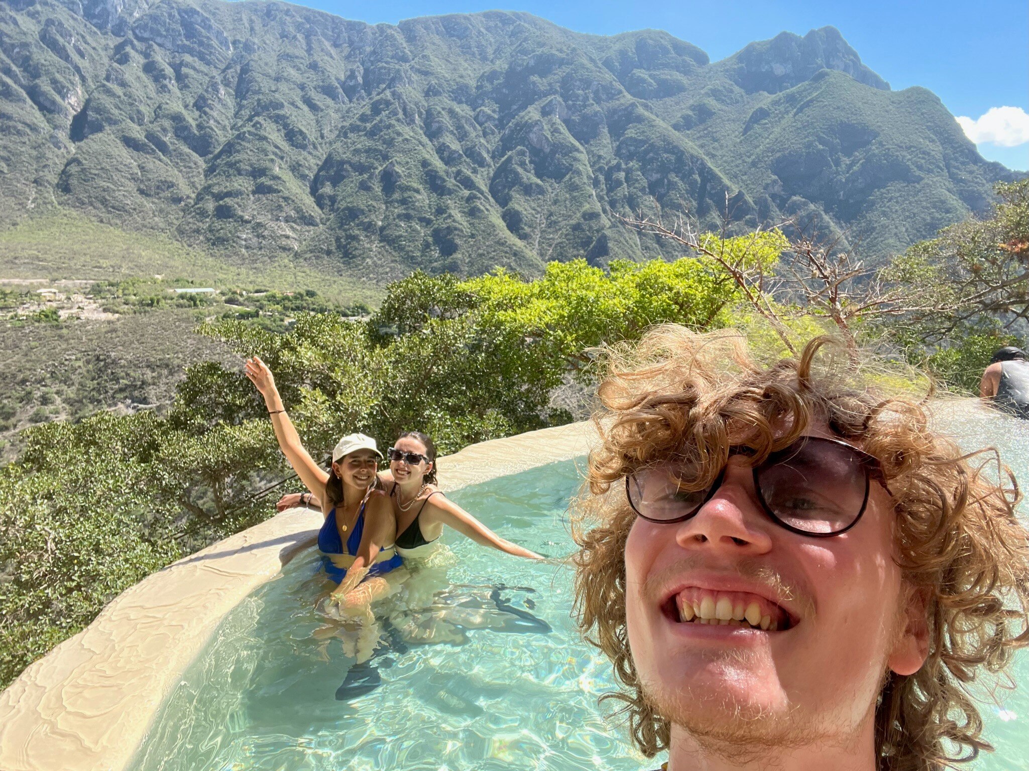 Tallis takes a selfie in an outdoor mountain pool with two friends.