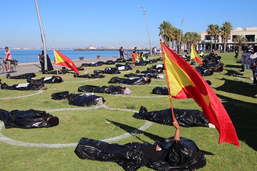 Dozens of Melbourne residents wear mock body bags as part of a protest at St Kilda beach