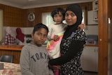 Asylum seeker, Soeharner holding her niece, with her brother Rishman in their home in Australia