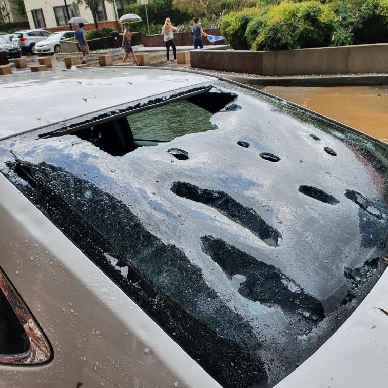 A parked car shows a windscreen smashed from hail.