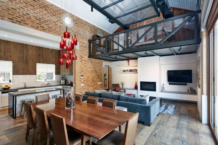 The interior of a building with open plan living room, exposed beams and brick work.