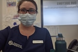 An image of angie walker in a mask, blue uniform at doctor clinic