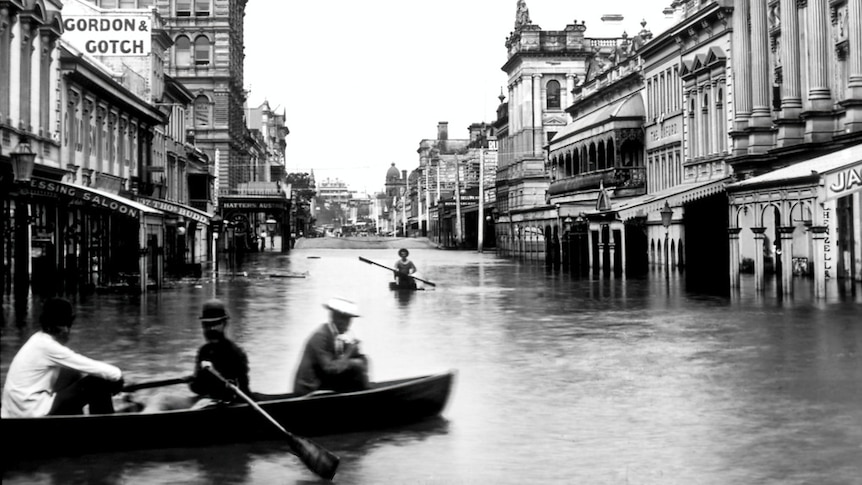 Historic photo of Brisbane's Queen Street after the 1893 show people passing through the street in row boats.
