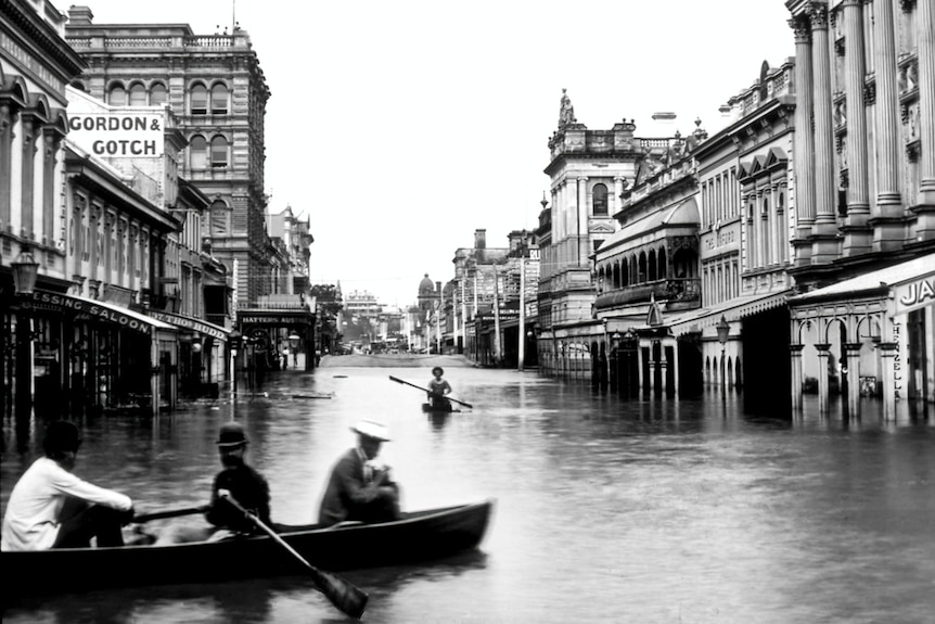 Historic photo of Brisbane's Queen Street after the 1893 show people passing through the street in row boats.