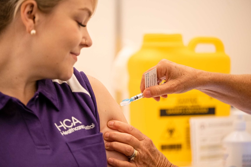 Ms Winks with her sleeve rolled up receiving a coronavirus vaccination from a syringe, from an unidentified doctor.