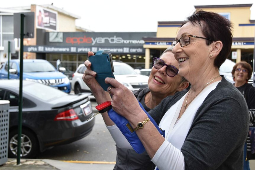 Smiling Albany locals Pamela Stoney and Robyn Martin take a photo on a mobile phone.