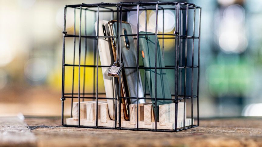 Mobile phones locked up with padlock in box with black metal bars