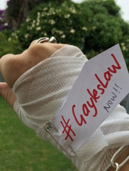 A social media post of a bandaged hand with a tag #GaylesLaw NOW!